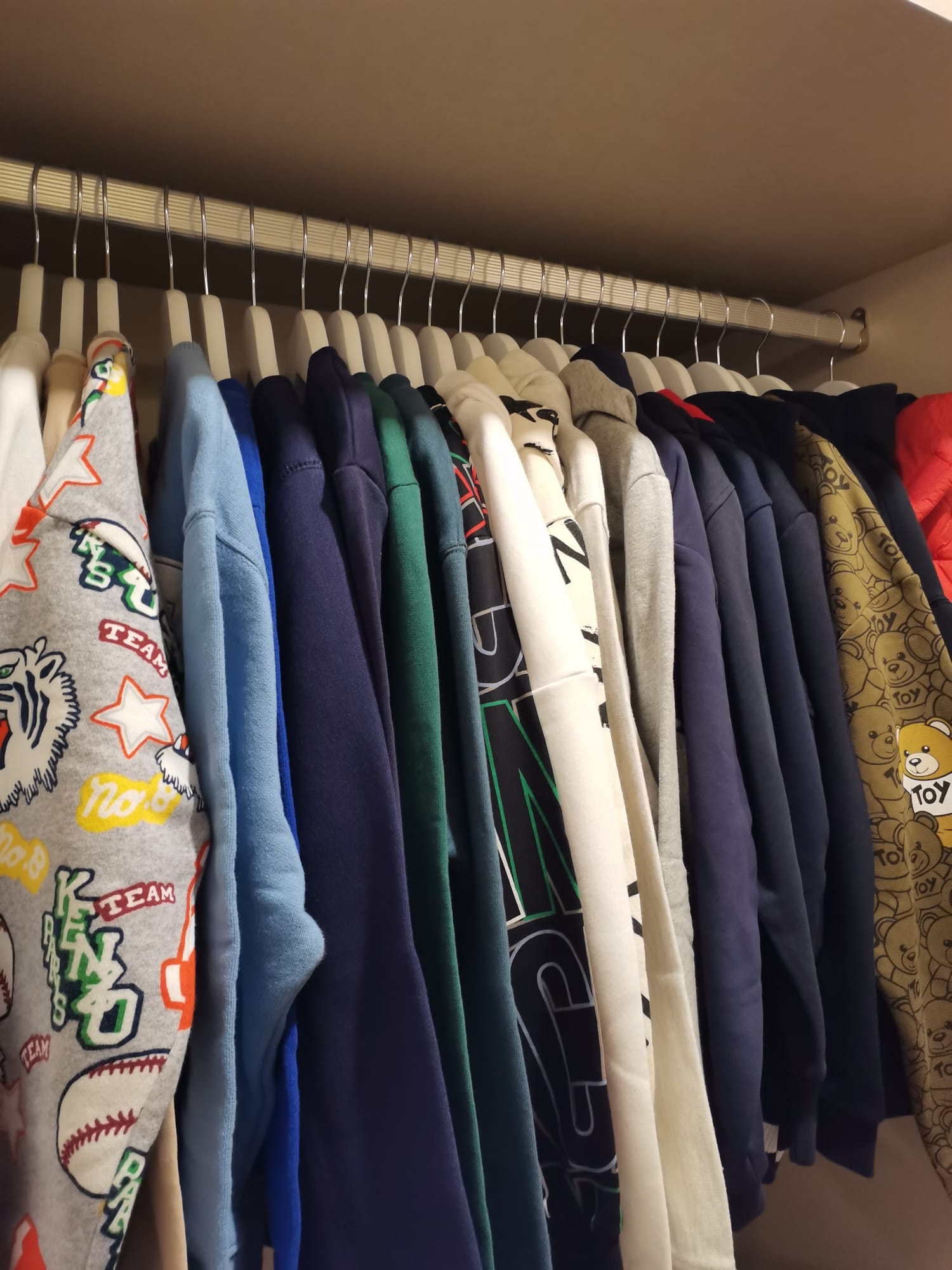 Roupeiro com camisolas e casacos pendurados e organizados por cor